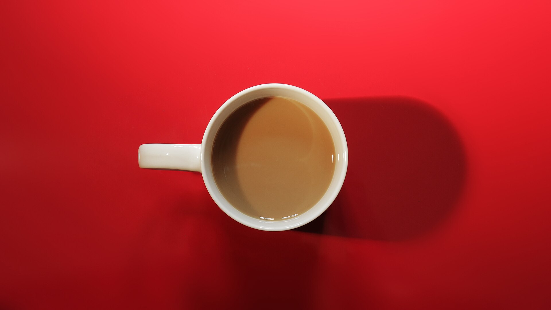 木のテーブルに置かれた、湯気を感じる一杯のコーヒー
